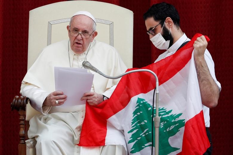 Pope Francis and a faithful hold a Lebanese flag as they pray for the country, following an explosion in Beirut, during the first weekly general audience to readmit the public since the coronavirus outbreak, in the San Damaso courtyard, at the Vatican. REUTERS/Guglielmo Mangiapane